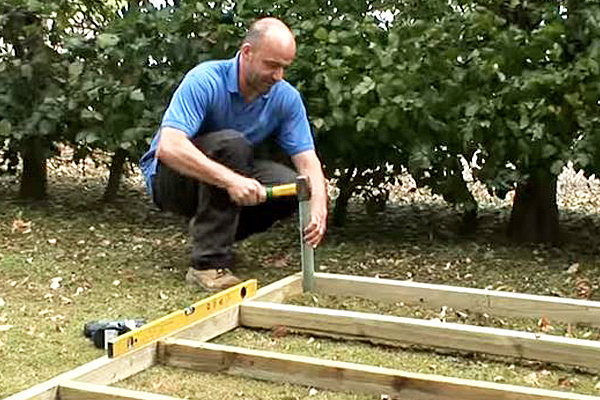 Driving in stake at corner of shed base framework